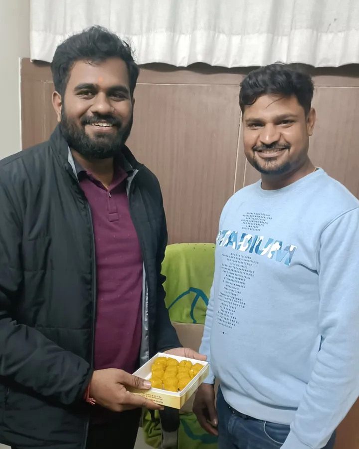 Harsh Kumar holding an open box of laddoos beside a member of the Vivekananda team at the institute, after his RRB PO result