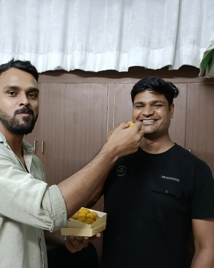 Shivam Bhatt being fed a sweet from a box of laddoos at the institute, after his ADEO selection