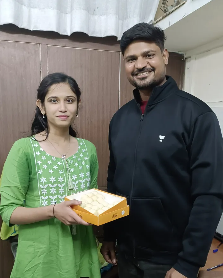 Jaya Narvariya holding a box of sweets at the centre after qualifying as a CA