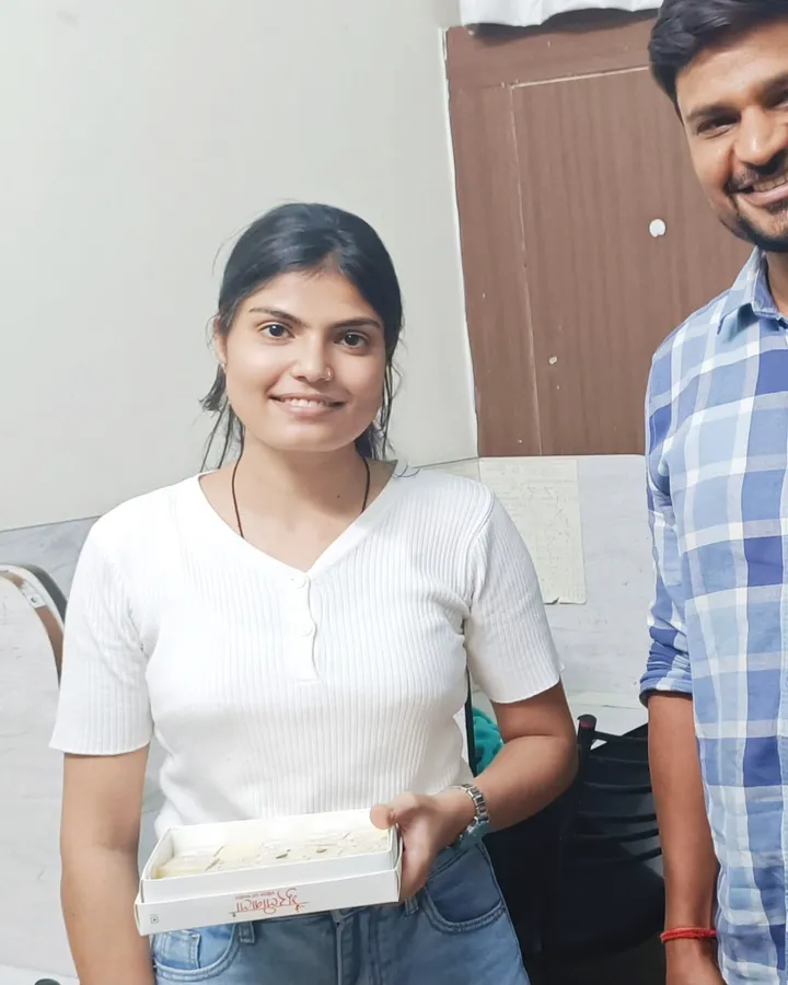 Sheetal Sekhawat holding a box of sweets at the centre, standing with a member of the Vivekananda team, after qualifying as a CA