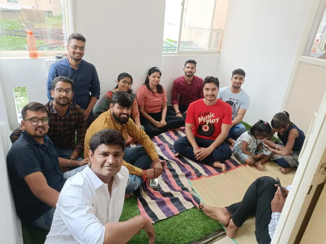 Students sitting together on a mat on the floor for a group photograph